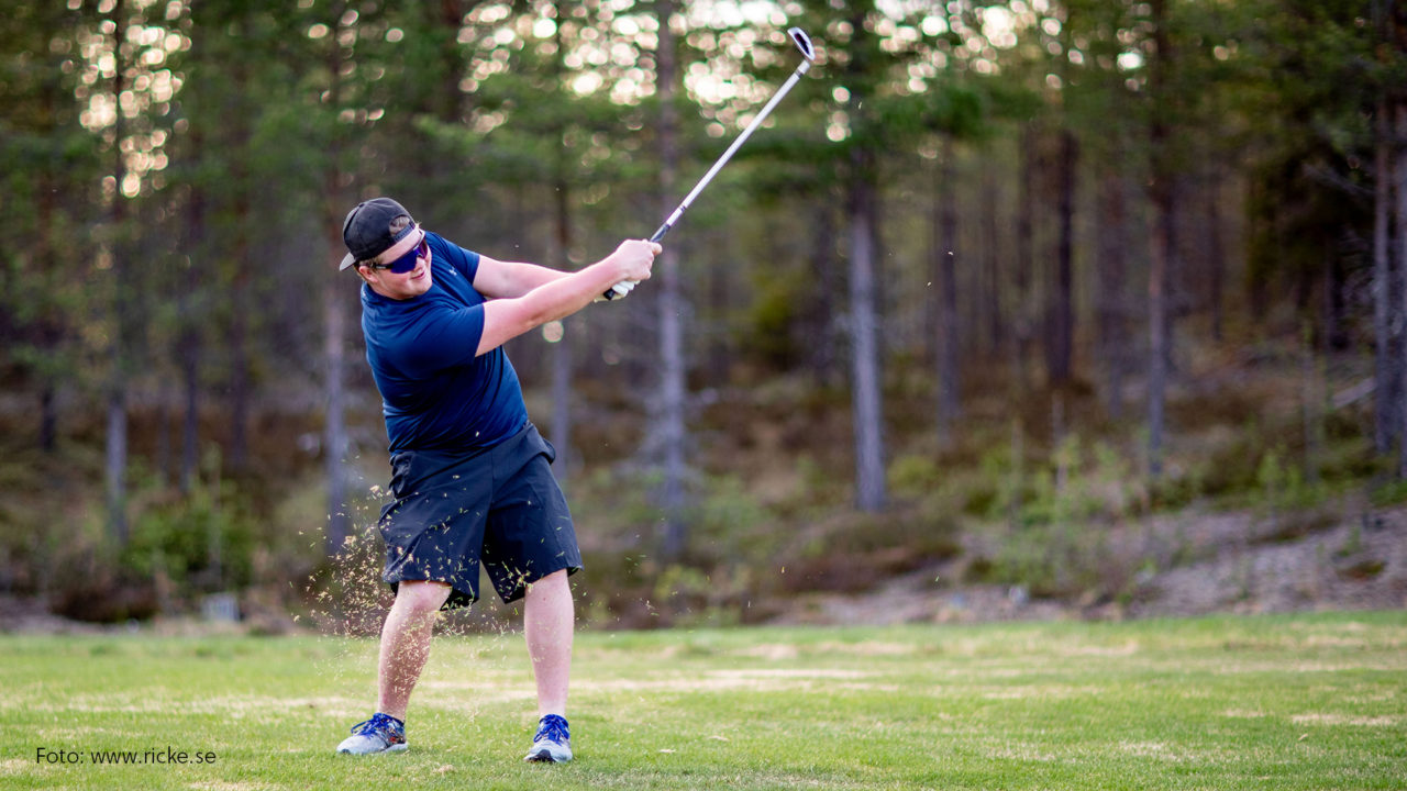 Kille som spelar golf.
