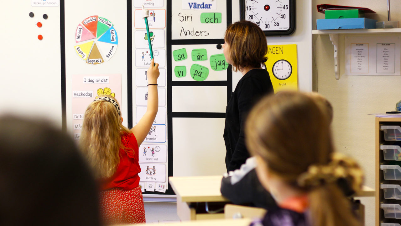 Flicka med lärare som står vid vita tavlan.