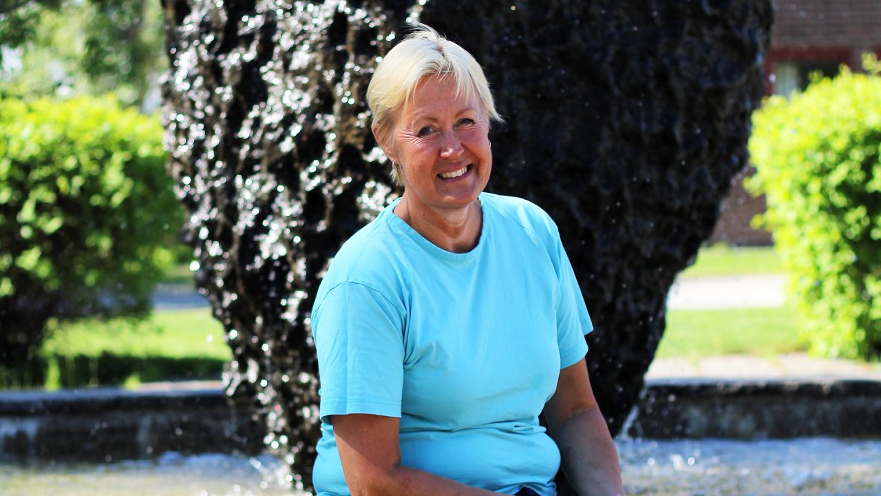 En glad Birgit framför stenen vid kommunhuset.