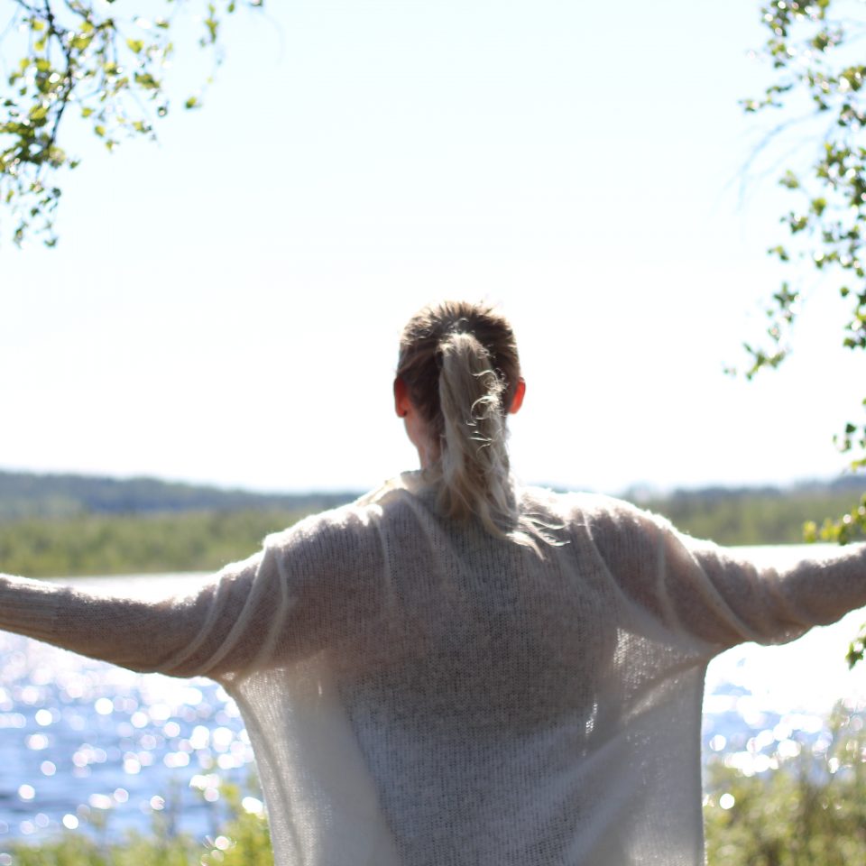 Kvinna som sträcker ut armarna. Ryggen vänd mot kameran.