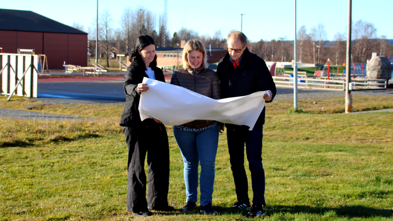 Två kvinnor och en man som tittar på en ritning.