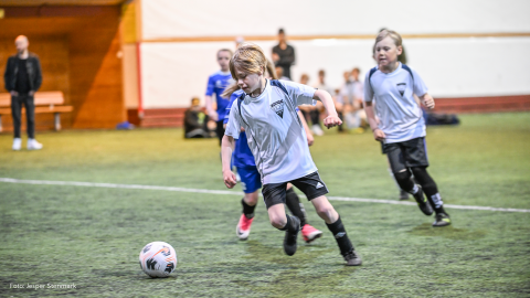 Ungdomar som spelar fotboll i en hall.