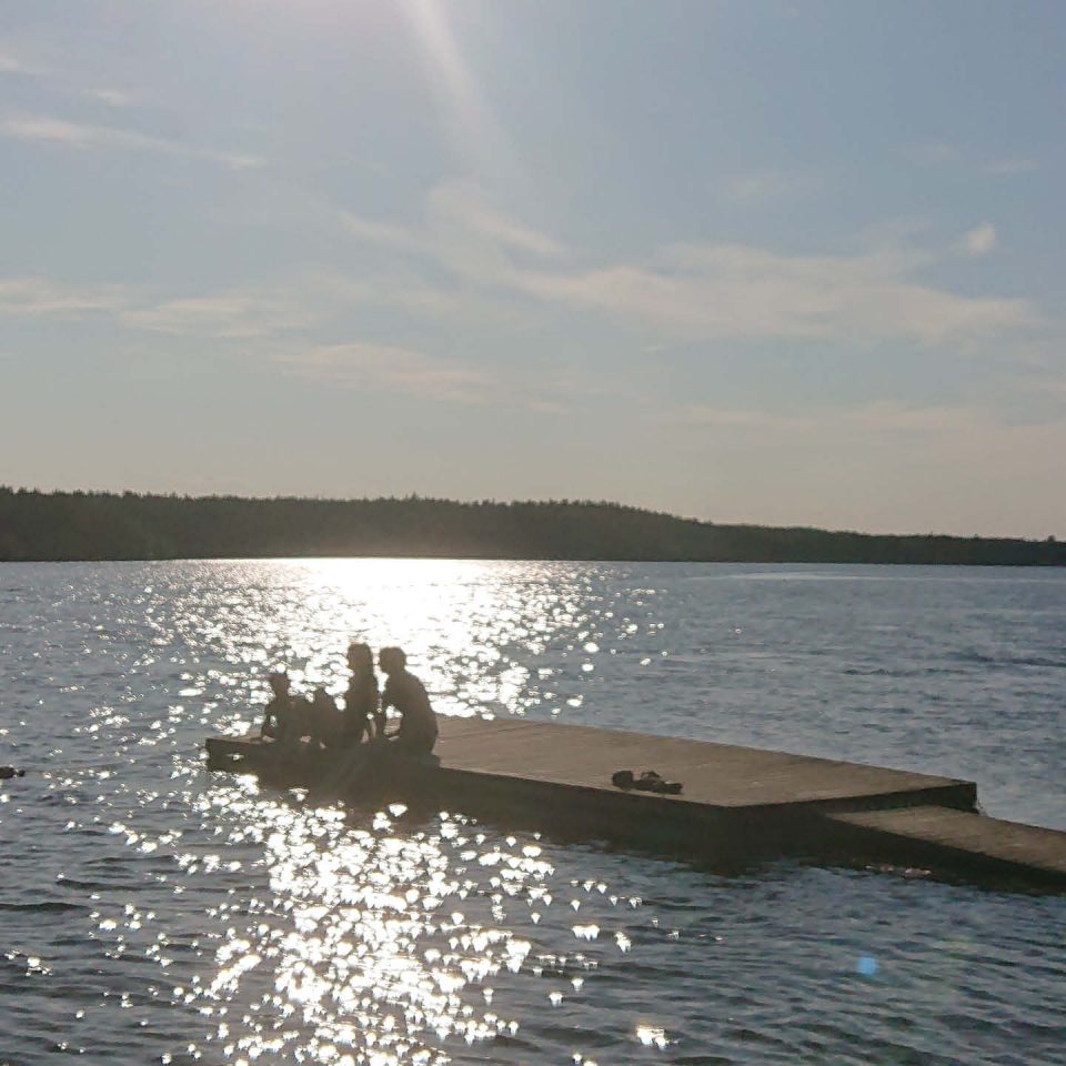 Ungdomar på en brygga. Motljus.