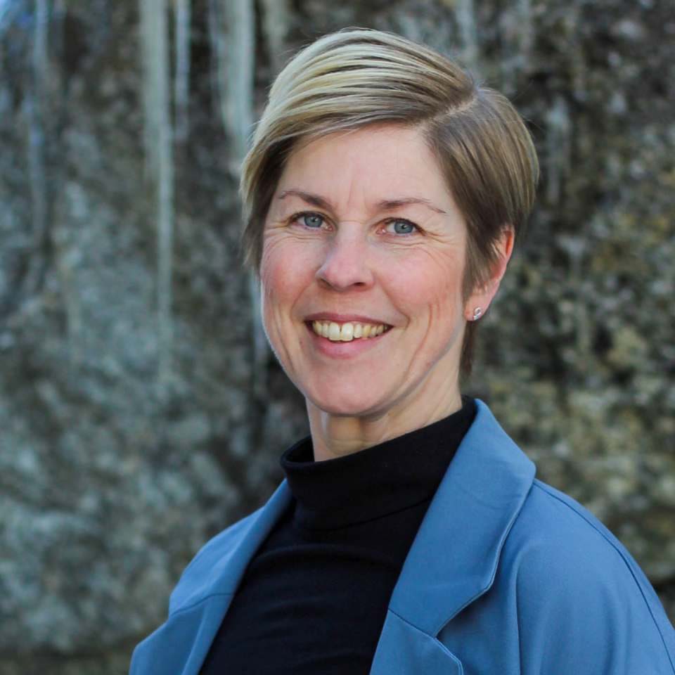 Glad kvinna i blå kavaj.