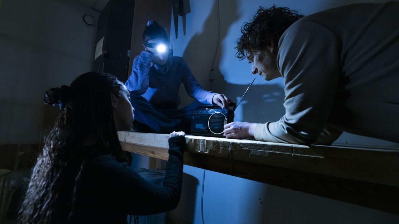 Tre personer som fixar med radion i mörkret.